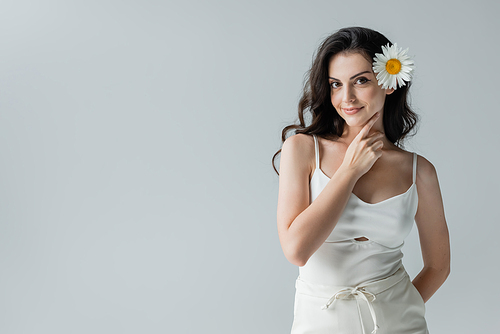 Pretty brunette woman with chamomile in hair posing isolated on grey