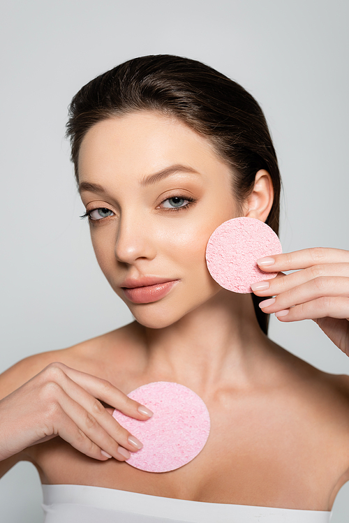 young woman holding organic exfoliating sponges isolated on grey