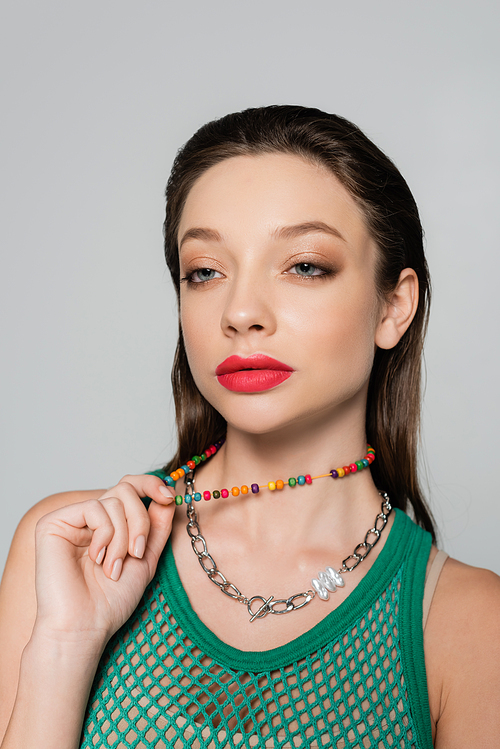 stylish model with red lips pulling beads necklace isolated on grey