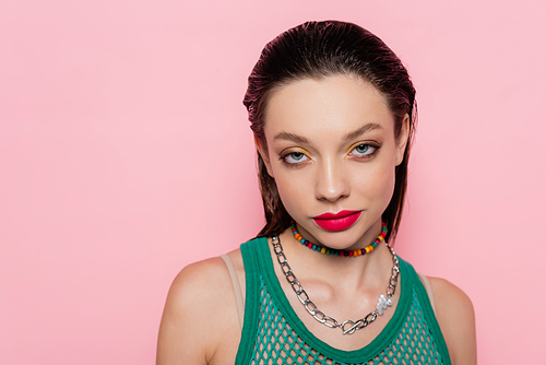 young brunette woman with bright makeup posing while looking at camera isolated on pink