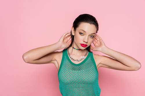 young brunette woman with bright makeup posing and looking at camera isolated on pink