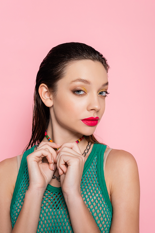 brunette young woman with bright makeup posing and looking at camera isolated on pink