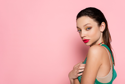 young brunette woman with bright makeup posing on pink background
