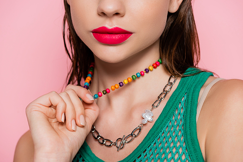 cropped view of young model with bright makeup posing while pulling necklace isolated on pink