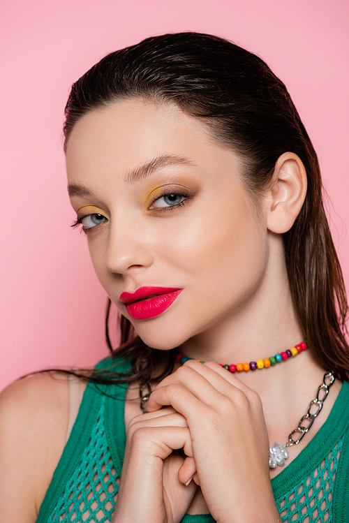 brunette model with bright makeup posing isolated on pink
