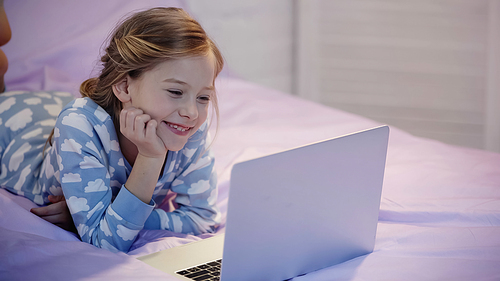 Happy preteen girl watching cartoons on laptop in bedroom