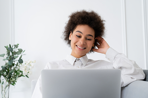 positive african american woman using laptop while working from home