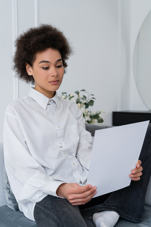 curly african american woman looking at blank document at home
