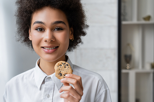 happy african american woman holding cookie with chocolate chips