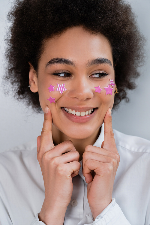 portrait of african american woman pointing with fingers at cheeks with decorative purple stars