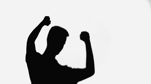 black shadow of man showing triumph gesture isolated on white