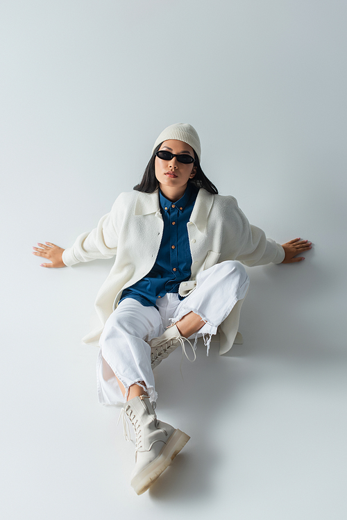 high angle view of asian woman in white clothes and dark sunglasses sitting on grey