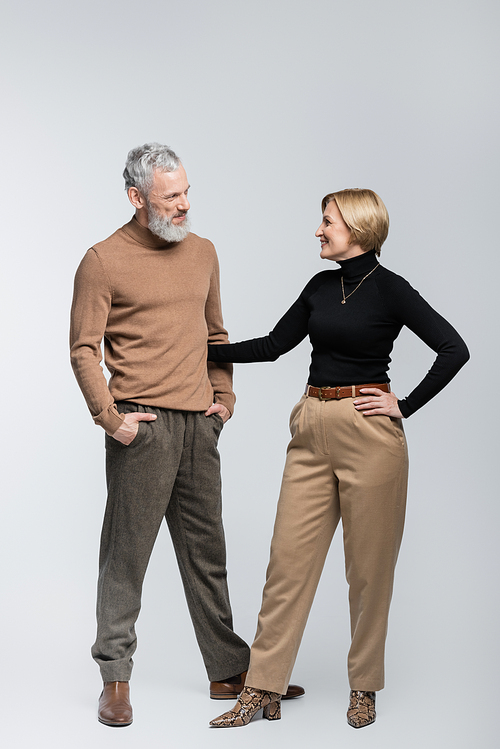 Positive stylish woman hugging husband on grey background