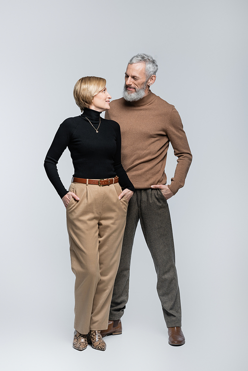 Trendy mature man looking at blonde wife on grey background