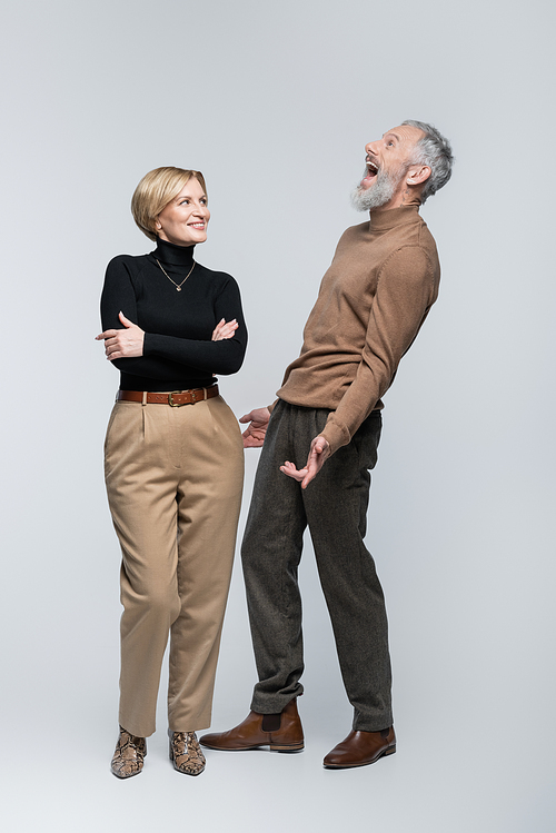 Excited mature man standing near stylish wife on grey background