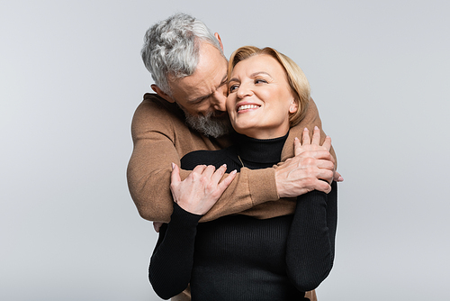 Grey haired man kissing and hugging wife isolated on grey