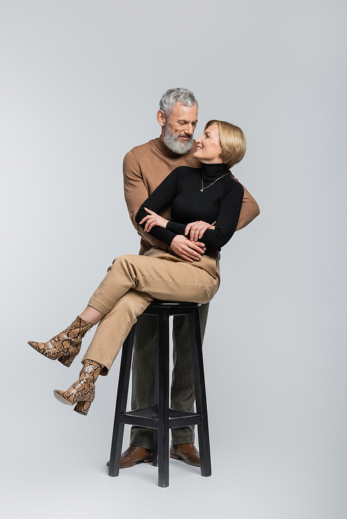 Happy mature couple hugging and looking at each other on grey background