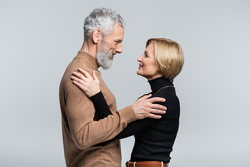 Side view of positive mature couple hugging isolated on grey