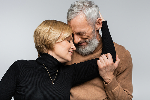 Portrait of mature woman hugging grey haired husband isolated on grey