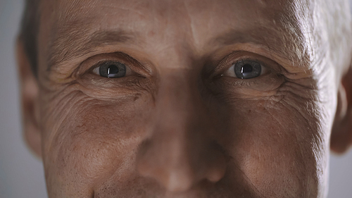 close up view of happy middle aged man with wrinkles looking at camera isolated on grey