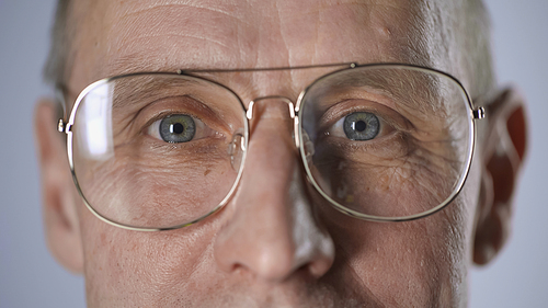 cropped view of middle aged man in eyeglasses looking at camera isolated on grey