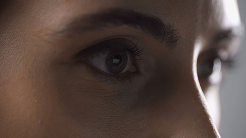 close up view of woman mascara on eyelashes looking away isolated on grey