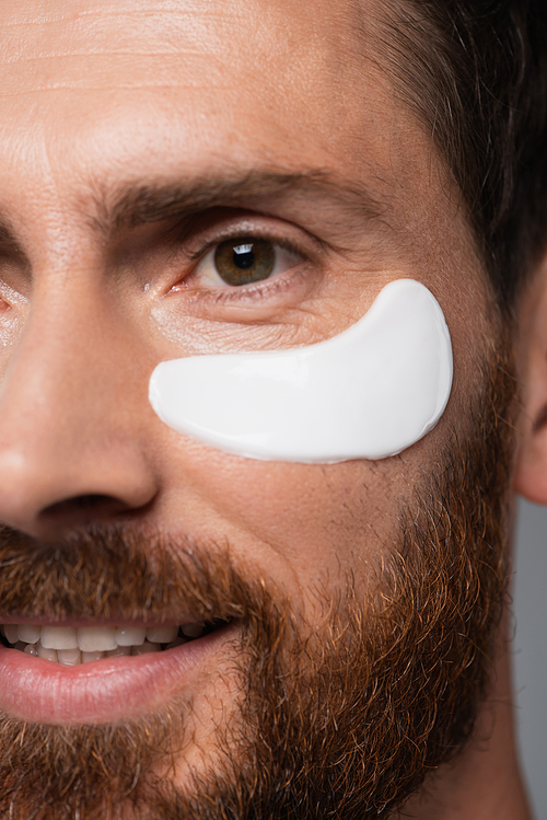 close up view of happy bearded man with moisturizing eye patch