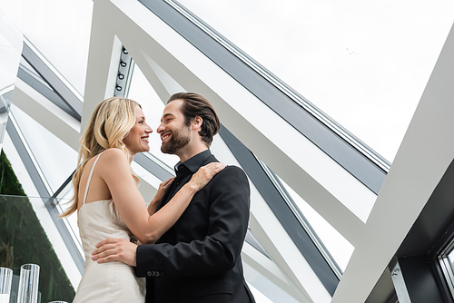 Low angle view of smiling elegant couple hugging in restaurant