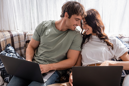 Positive couple using laptops on bed in camper van