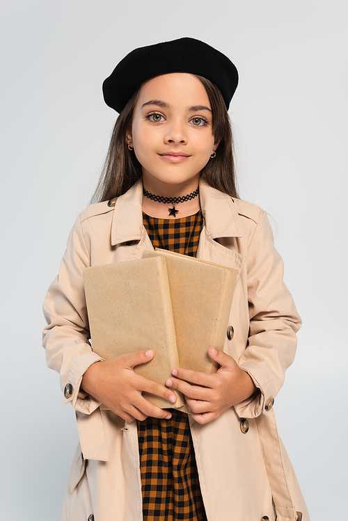 cute girl in stylish autumnal outfit and beret holding books isolated on grey