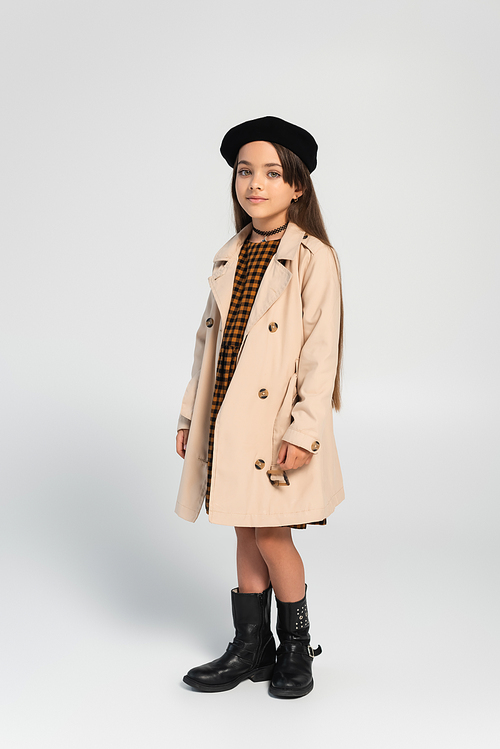 full length of adorable girl in stylish trench coat and beret posing on grey