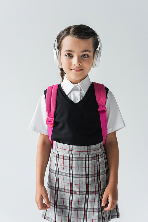 happy schoolgirl in wireless headphones listening music isolated on grey