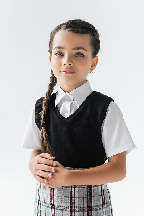 portrait of schoolgirl with white shirt and vest looking at camera isolated on grey