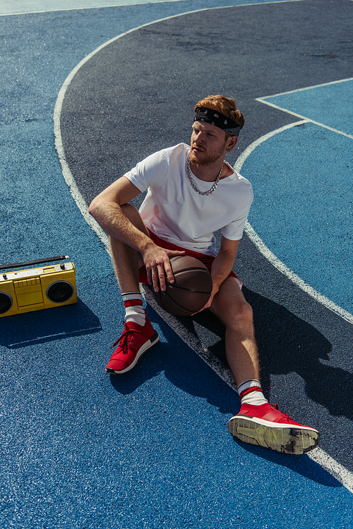 high angle view of sportsman in bandana sitting on court near boombox