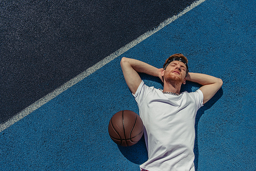 top view of young basketball player relaxing on court near ball