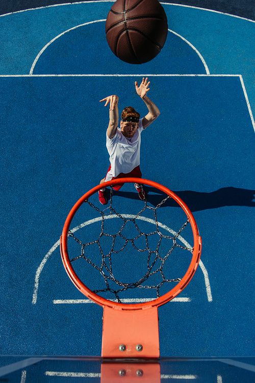 top view of man throwing ball into basketball hoop