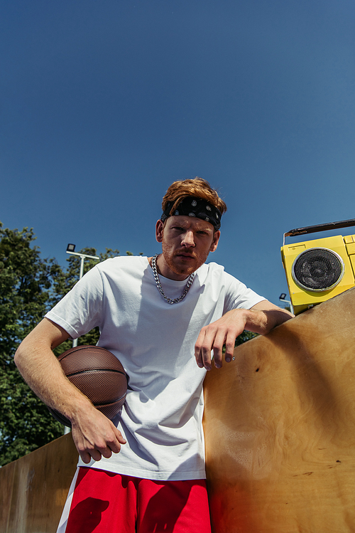 low angle view of sportsman with ball looking at camera near retro boombox
