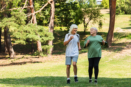 full length of senior couple in sportswear running in green park