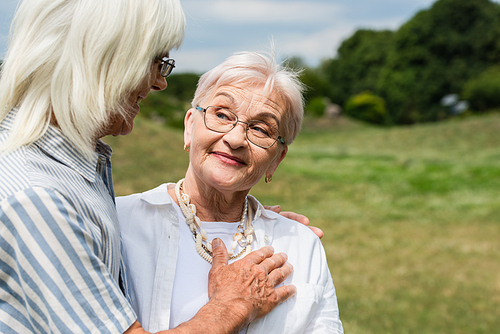 happy senior man in glasses putting hand on chest of smiling wife