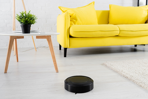 Robotic vacuum cleaner on floor near coffee table in living room
