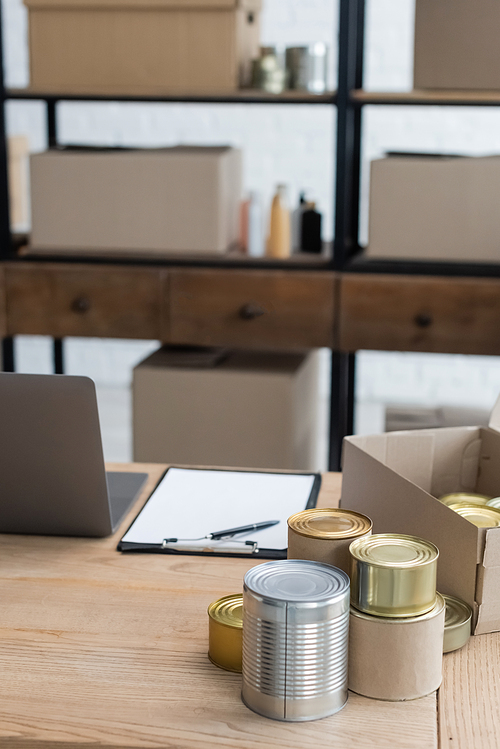 canned food and clipboard near laptop on desk in charity center