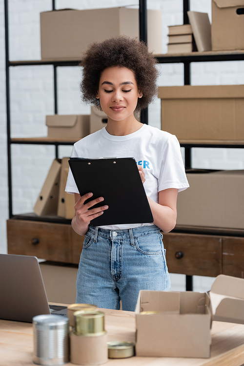 positive african american woman with clipboard working in donation center