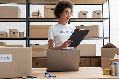 african american volunteer looking at clipboard while working in donation center