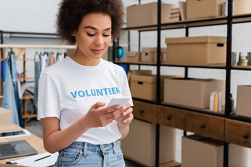 young african american volunteer using mobile phone in donation center