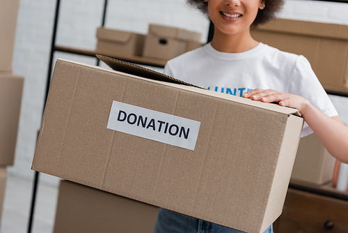 cropped view of blurred african american woman holding box with donation lettering