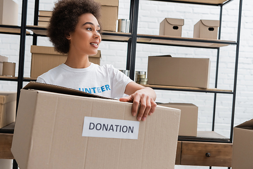 young african american volunteer holding donation box in charity center