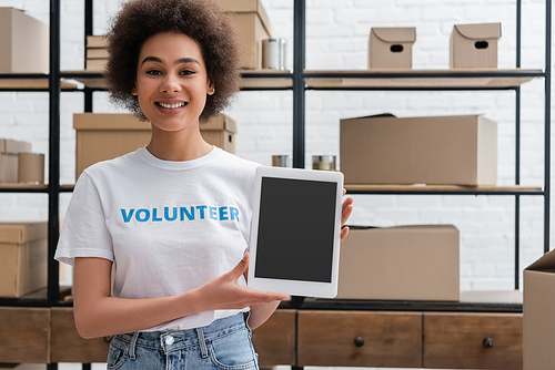 happy african american volunteer showing digital tablet with blank screen