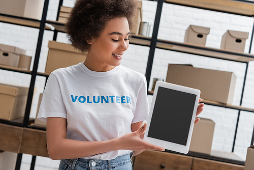 smiling african american woman holding digital tablet with blank screen in donation center