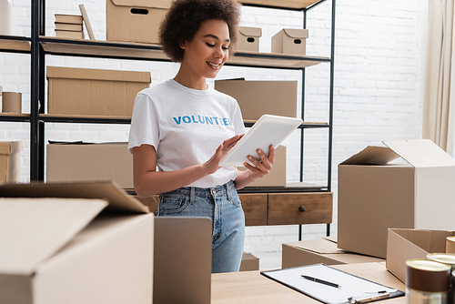 smiling african american volunteer using digital tablet while working in warehouse