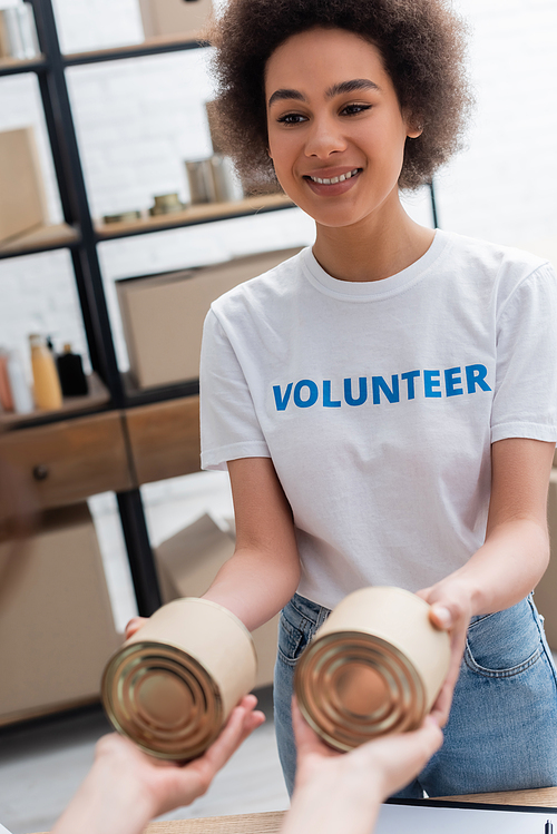 young african american woman handing out humanitarian aid in volunteer center